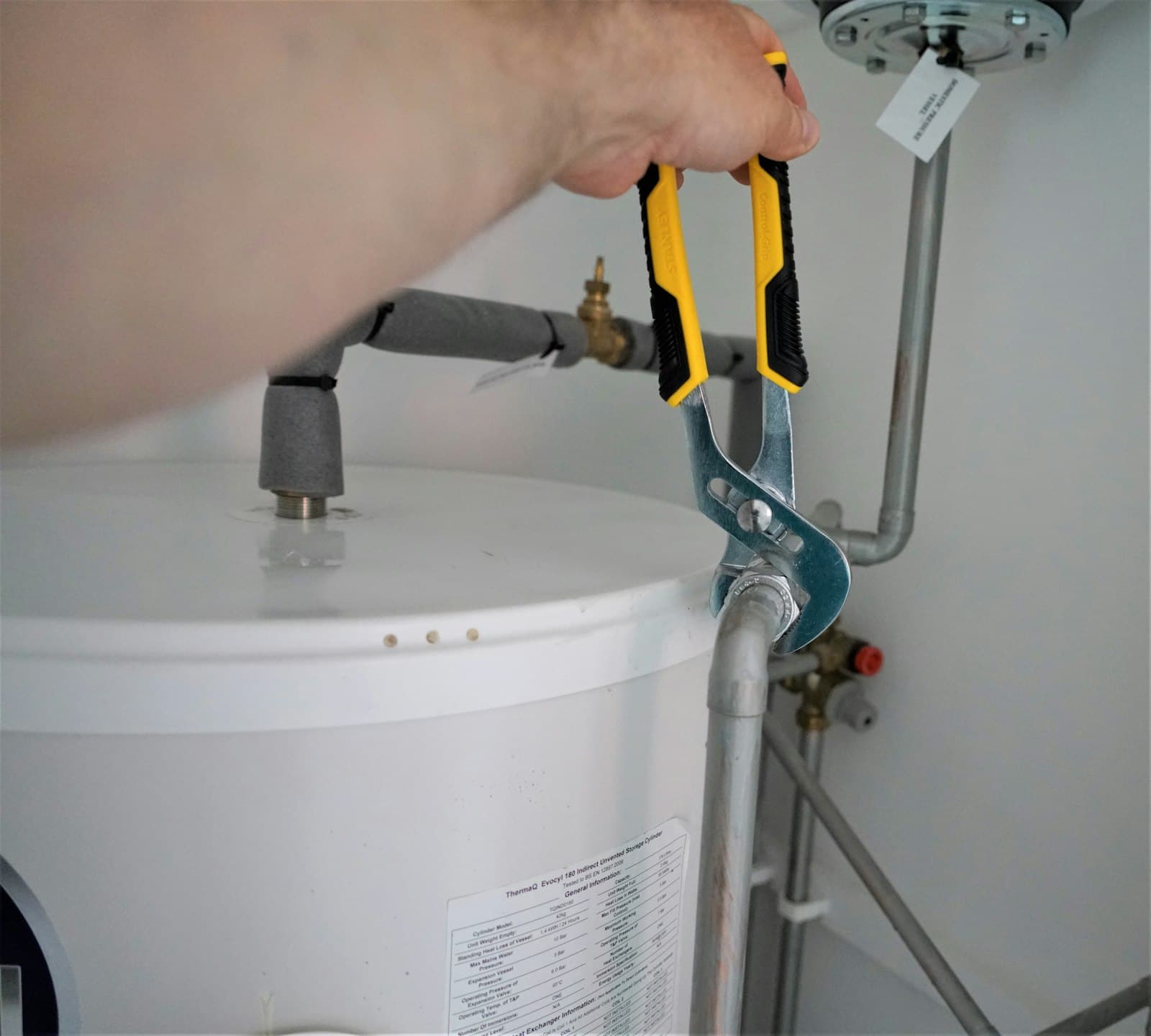 Plumber using pliers to connect a fitting on a water heater