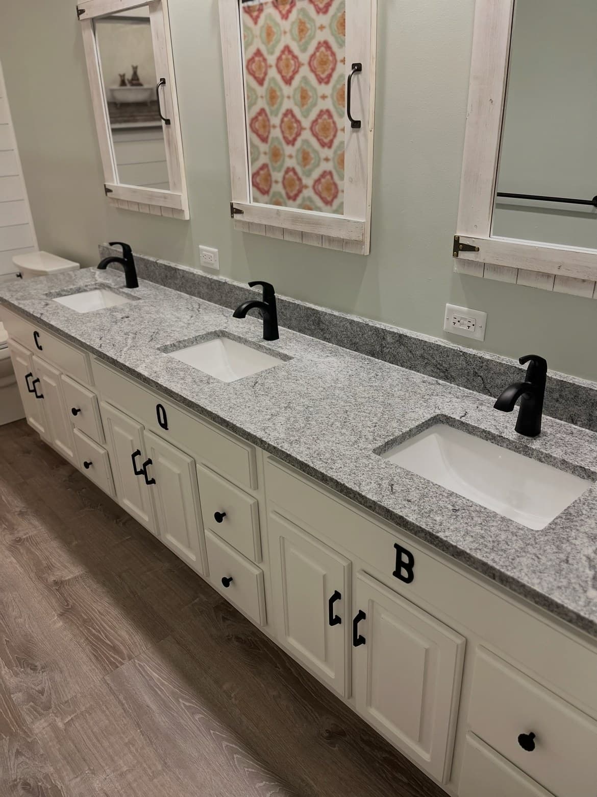 Finished triple-sink vanity bathroom with granite countertops by Lucas Plumbing, greater Boston